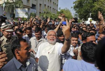 Hindu nationalist Modi shows his ink-marked finger to his supporters after casting his vote in Ahmedabad